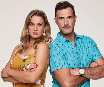 Two people standing back-to-back, arms crossed, wearing a yellow floral dress and a blue patterned shirt.