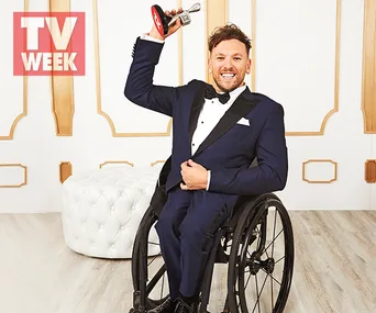 Man in a wheelchair holding an award, smiling, wearing a tuxedo, with a "TV Week" logo on the top left.