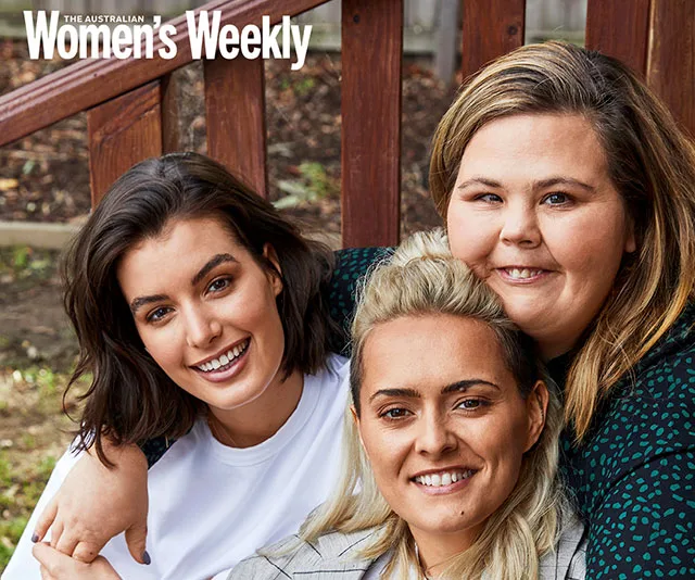 Three women smiling while sitting closely together outdoors on a bench, featured in Women's Weekly magazine.