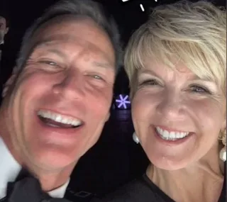 Two people smiling widely in a close-up selfie at an event.