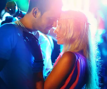 A couple intimately close in a colorful, vibrant setting, with soft lighting and festival-like atmosphere.
