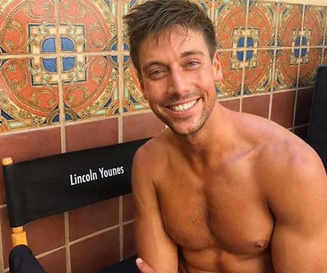 A shirtless man smiles next to a chair labeled "Lincoln Younes" against a tiled background.