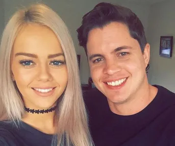 A smiling man and woman taking a selfie together indoors.