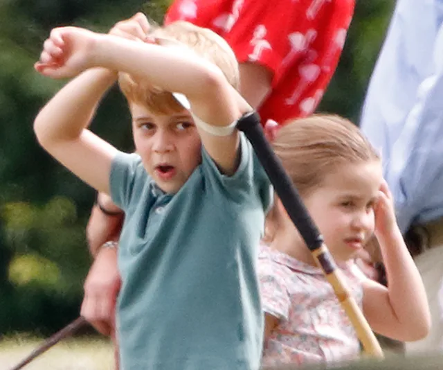 Two young children playing outdoors, boy holding a stick, both looking curious and engaged.