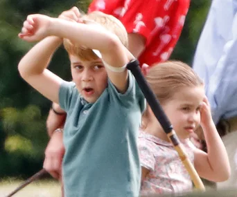 Two young children playing outdoors, boy holding a stick, both looking curious and engaged.