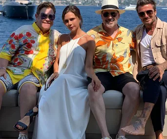 Four people sitting on a yacht, smiling and dressed for a sunny day on the water.