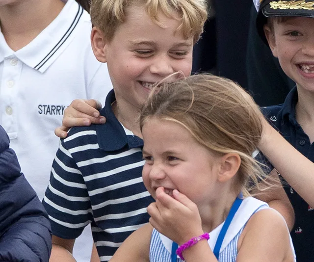 Children smiling and posing together, one in a striped shirt and another in a blue and white outfit.