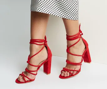 Red block heels with ankle straps paired with a black and white polka dot skirt.