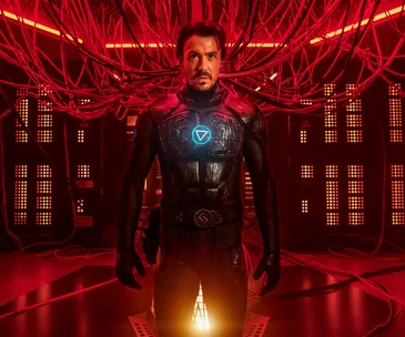 Character in futuristic suit with glowing symbol stands in a room filled with red cables and lights, from "Nekrotronic".