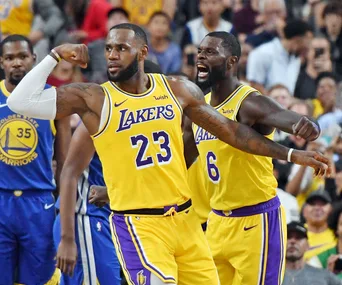 Basketball players in Lakers jerseys celebrate on the court; player 23 flexing muscles.