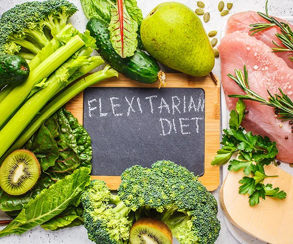 Fresh vegetables, fruits, and meat arranged around a chalkboard with "Flexitarian Diet" written on it.