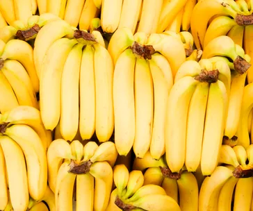 Bunches of ripe yellow bananas displayed closely together.