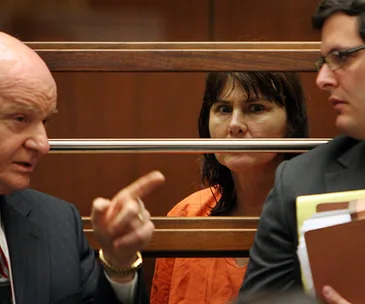 Stephanie Lazarus in court wearing an orange jumpsuit, with two men discussing in foreground.