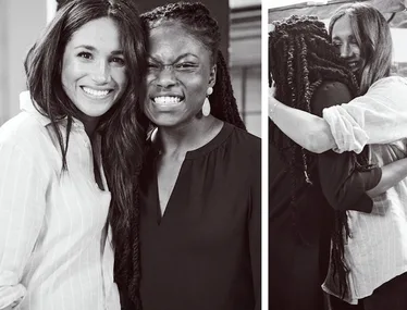 Two women smiling and embracing, one wearing a striped shirt, the other with braided hair and earrings, in a friendly moment.