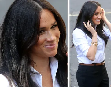 Meghan Markle smiling in a white shirt and black pants, part of the Smart Works Capsule Collection launch event.