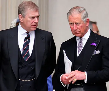 Two men in formal suits talking seriously, one holding a document.