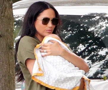 I don’t know who this is, but it shows a woman holding a baby wrapped in a blanket outdoors.