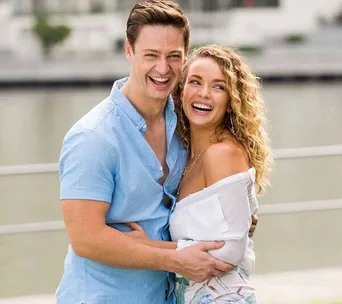 A couple, a man and woman, are happily embracing and laughing outdoors.