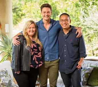 Group photo of three people smiling and posing together outdoors.