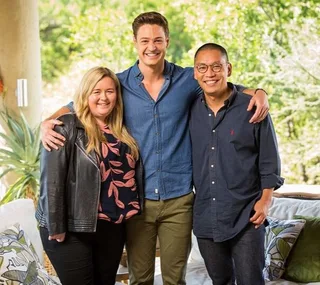 Group photo of three people smiling and posing together outdoors.