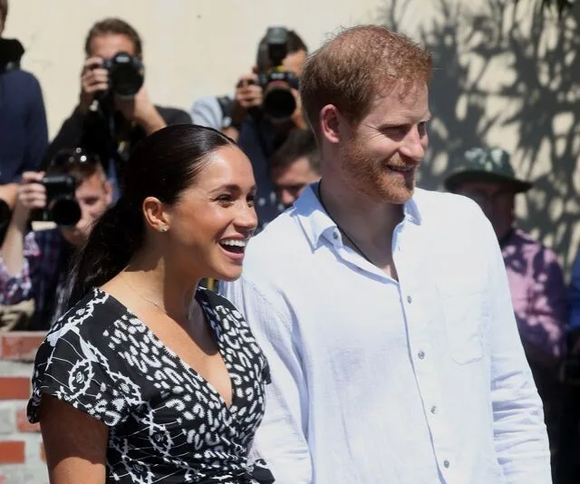 Royal couple smiling while photographers capture their arrival in South Africa.