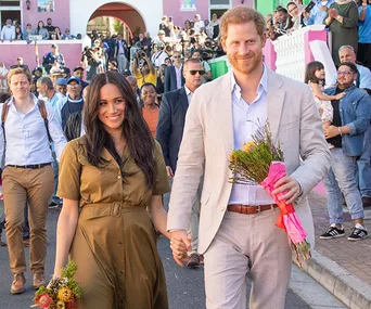 A couple holding flowers and hands, walking through a crowd in South Africa.