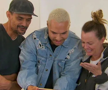 Three people looking at something, smiling and appearing pleasantly surprised.