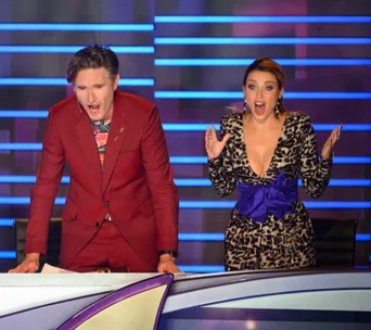 Judges on "The Masked Singer" reacting with surprise, standing at a desk, with a colorful background.