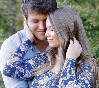 A couple embracing tenderly outdoors, with a soft-focus greenery background.