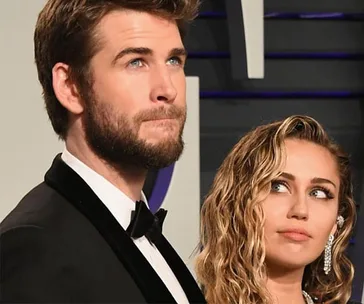 A man and woman in formal attire at an event, with her gazing up at him.