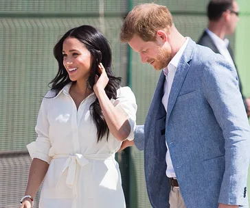 Prince Harry and Meghan Markle smiling and walking together during their Africa tour.
