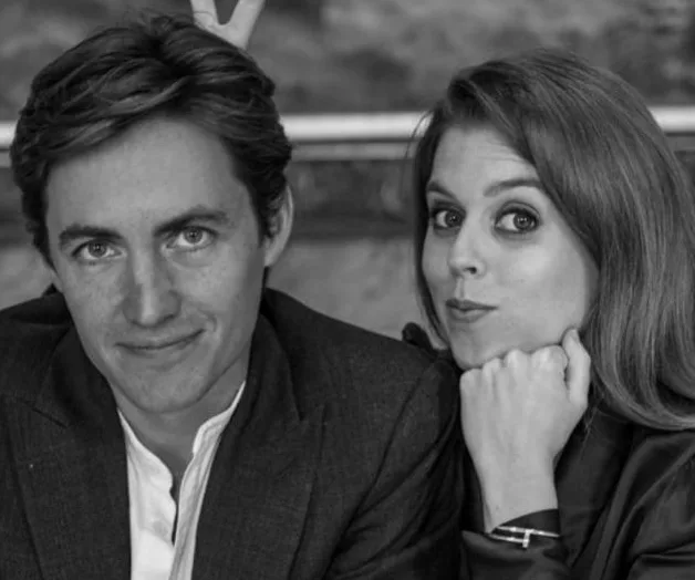 Two people posing playfully; one gives bunny ears, the other rests on their hand, smiling slightly.