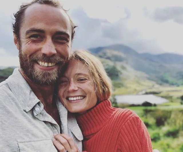 A couple smiling with a mountainous landscape in the background.