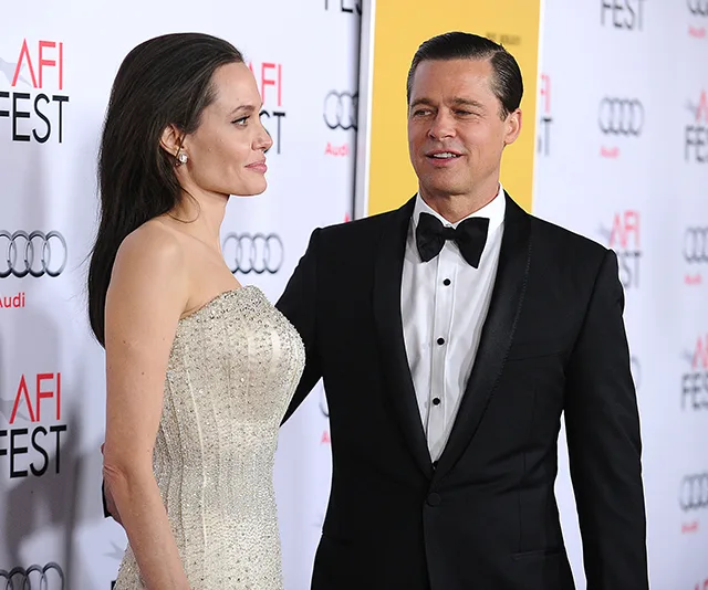 A man in a suit and a woman in a gown at a formal event with AFI Fest backdrop.