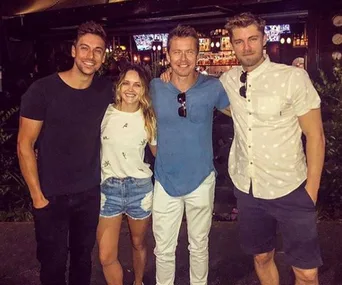 Group photo of four people smiling at a bar, with two men, a woman, and another man, casually dressed in evening wear.