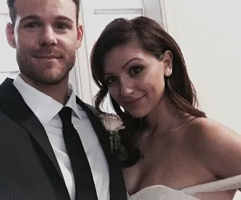 A couple dressed in formal attire, posing closely and smiling.