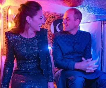Two people seated inside a colorful vehicle, smiling at each other while dressed in formal attire.