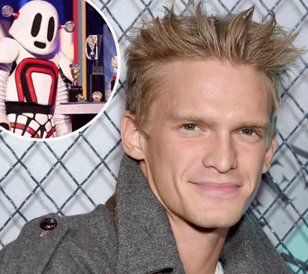 Cody Simpson with a smiling expression; inset shows the Robot costume from The Masked Singer.