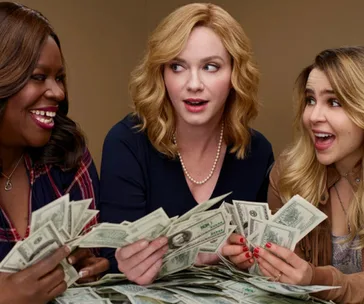 Three women happily counting stacks of cash, showing excitement and joy.