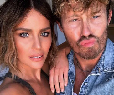 Two people taking a close-up selfie, one with wavy hair and a natural makeup look, the other with curly hair and a playful expression.