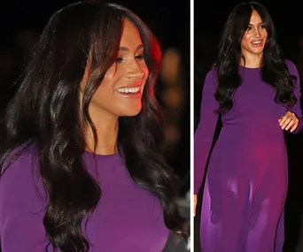 A woman with long dark hair in a elegant purple dress, smiling and walking at an evening event.