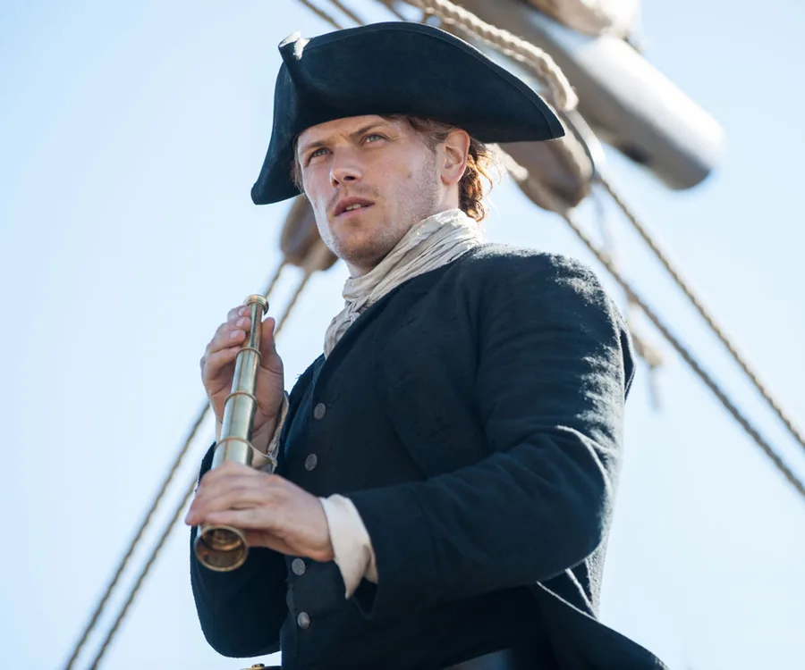 "Man in historical attire on a ship holding a telescope, looking into the distance under a clear sky."