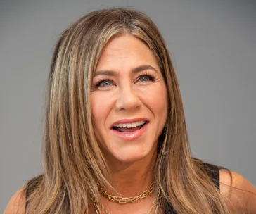 I don't know who this is, but it's a woman with long hair and a necklace smiling.