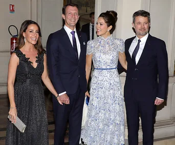 Four elegantly dressed people posing together indoors at an event.