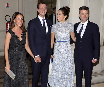 Four elegantly dressed people posing together indoors at an event.