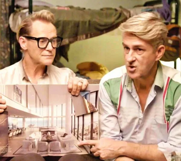 Two people in a room discussing interior design plans, one holding and pointing at a photo of a modern living space.