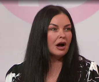 A woman with long black hair is speaking during an interview on a TV show.