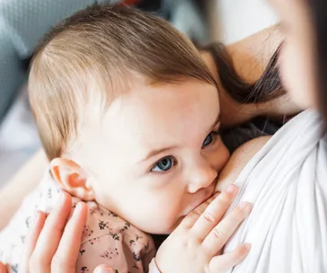 Baby breastfeeding and gazing up at the mother.