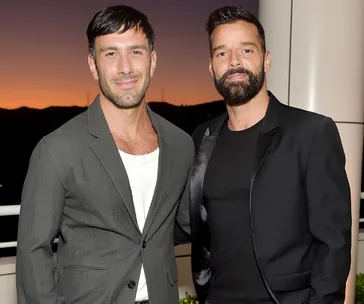 Two men in formal attire posing together with a sunset in the background.