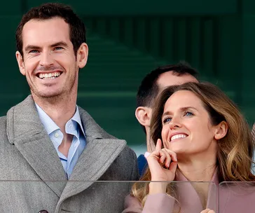 A happy couple standing together, both smiling brightly, dressed in formal attire.